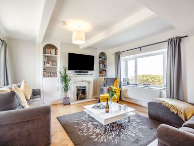 A living room with sofas a yellow armchair a white coffee table and a fireplace at Tyn Y Berth in Benllech