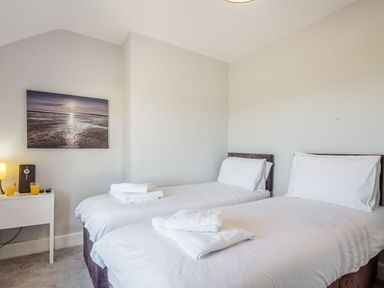 A bedroom with two single beds and a nightstand with two glasses of orange juice at Tyn Y Berth in Benllech