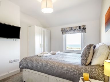 A bedroom with a double bed two white wardrobes and a window with a view at Tyn Y Berth in Benllech