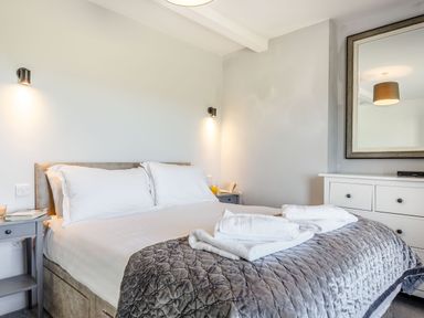 A bedroom with a bed with white pillows and gray quilt on the bed at Tyn Y Berth in Benllech