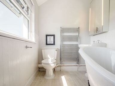 A bathroom with a toilet bathtub sink and heated towel rail at Tyn Y Berth in Benllech