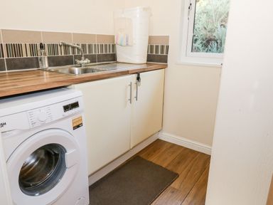 A laundry room with a washing machine sink and cabinets at The Wee Lodge in Dollar