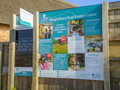 An outdoor signboard with information about Hengistbury Head Visitor Centre including wildlife garden exhibitions gift shop and free entry at Hengistbury Head Visitor Centre in Tuckton