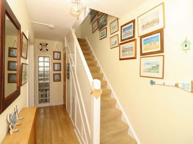 A hallway with a staircase and wall art at 32 Cranleigh Close Tuckton
