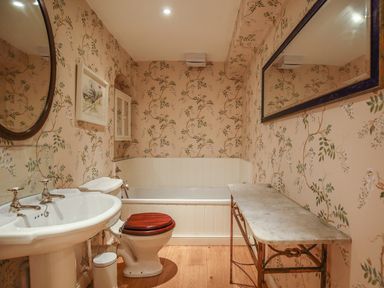 A bathroom with a sink toilet bathtub mirror and marble table at All Souls Cottage in Eastleach Cotswolds