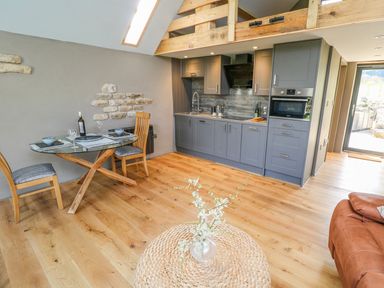 A kitchen and dining area with grey cabinets and wooden table at Thompson Rigg Barn Langdale End near Thornton Dale