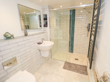 A bathroom with a wall-mounted sink mirror glass shower and towel rack at Thompson Rigg Barn Langdale End near Thornton Dale