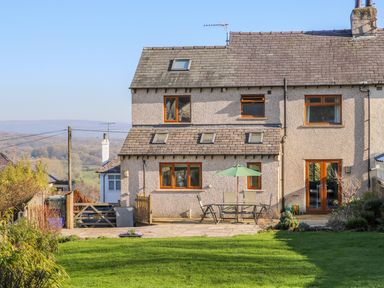 A house with a patio table and umbrella in a garden with green grass at Langtree in Arnside