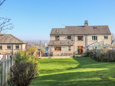 A backyard with a lawn and patio furniture behind a two story house at Langtree in Arnside