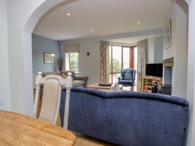 A living room with a sofa, armchair, and television at Langtree in Arnside