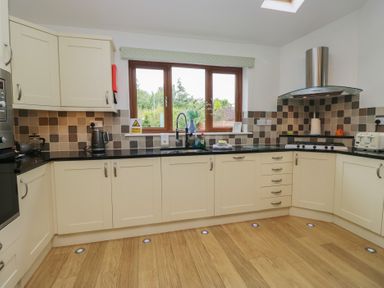 A kitchen with cabinets and a window at Langtree in Arnside