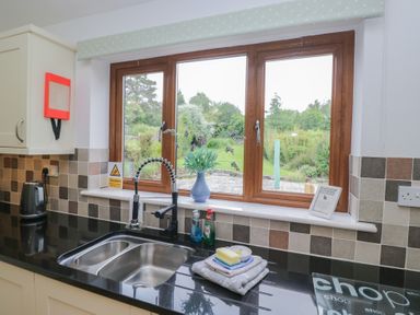 A kitchen with a sink and window overlooking the garden at Langtree in Arnside