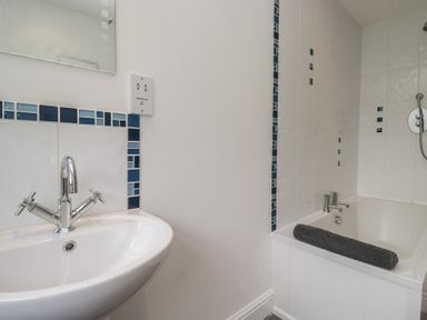 A bathroom featuring a washbasin and bathtub at Langtree in Arnside