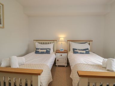 A bedroom with two beds and a bedside table with a lamp at Langtree in Arnside