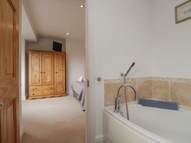A bathroom with a bathtub and a wardrobe at Langtree in Arnside