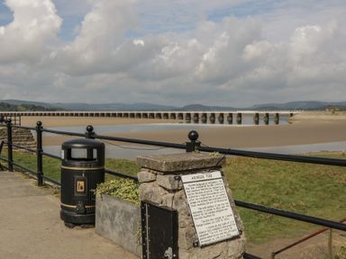 A view of Arnside Pier with a trash can and information plaque in Arnside