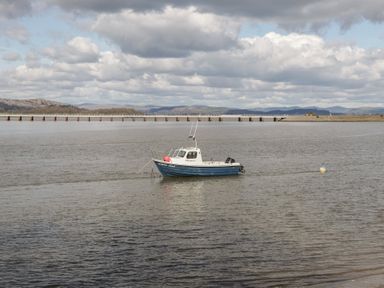 A boat on water with a pier in the background at Langtree in Arnside