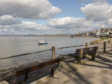 A view of a river with a boat and benches at Langtree Arnside
