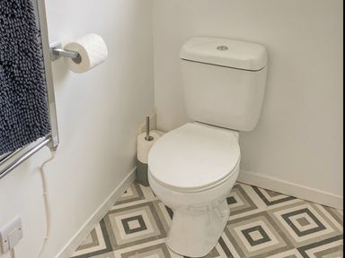 A toilet with a toilet paper holder and two toilet paper rolls in a bathroom at Ty Gilbert in Benllech