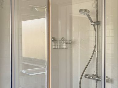 A shower area with a handheld showerhead and a metal soap holder at Ty Gilbert in Benllech