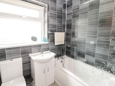 A bathroom with a toilet sink and bathtub with shower at Ty Gilbert in Benllech