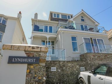A multi-story residential building with balconies and glass railings and a car parked outside at 1 Lyndhurst in Salcombe