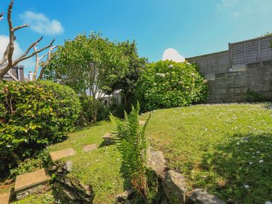A garden with grass lawn stone steps and various shrubs and trees at 1 Lyndhurst in Salcombe
