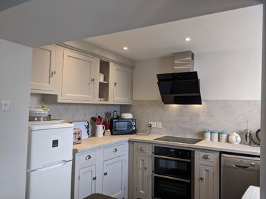 A kitchen with white cabinets white refrigerator black oven and microwave at Rose Cottage in Lowick Bridge
