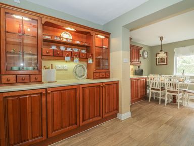 A kitchen with wooden cabinets and a dining table with chairs at Humble Bee Cottage in Wold Newton near Hunmanby