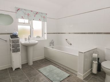 A bathroom with a bathtub sink toilet and storage unit at Humble Bee Cottage in Wold Newton near Hunmanby