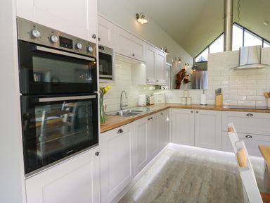 A kitchen with double ovens a sink countertop cabinets and chairs at Restharrow Lodge in Bamburgh