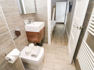A small bathroom with a toilet and sink looking into a bedroom at Restharrow Lodge in Bamburgh