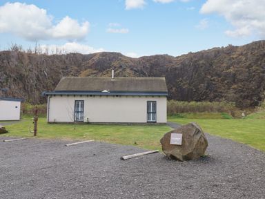 A single story building with two windows and a grassy area in front at Restharrow Lodge in Bamburgh