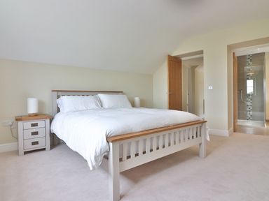 A bedroom with a bed a bedside table with a lamp and a view of a bathroom at The Retreat in Lympsham