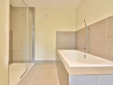 A bathroom with a bathtub and a glass-enclosed shower at The Retreat in Lympsham