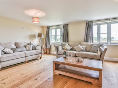 A living room with two sofas pillows coffee table and lamp at The Retreat in Lympsham