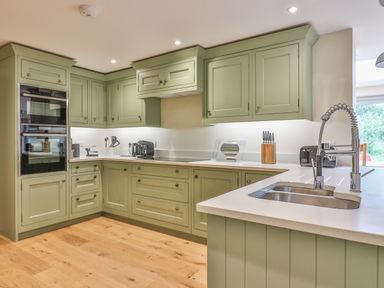 A kitchen with green cabinets wooden floor and a countertop with sink at The Retreat in Lympsham