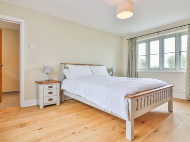 A bedroom with a double bed bedside tables and lamps by a window at The Retreat in Lympsham