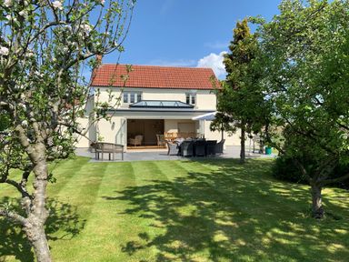 A house with an open patio area dining set and trees in the garden at The Retreat in Lympsham