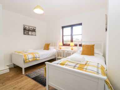 A bedroom with two single beds and a window at Stable Cottage in Shipham