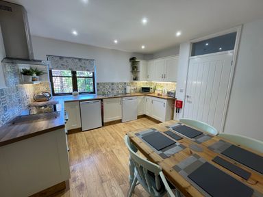 A kitchen with wooden floor cabinets countertop dining table and chairs at Stable Cottage in Shipham
