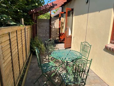 An outdoor patio area with green metal table and chairs next to a beige building at Stable Cottage in Shipham
