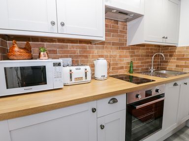 A kitchen counter with microwave toaster kettle stove sink and cabinets at Bwlch Y Gwynt Bach in Llangefni
