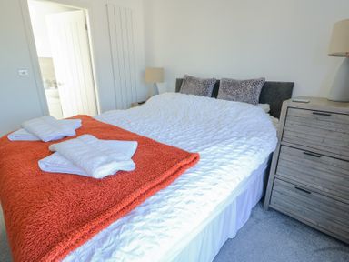 A bedroom with a bed covered in white and orange blankets and white towels on the bed at Bwlch Y Gwynt Bach in Llangefni