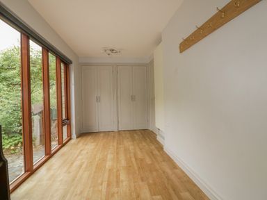 A room with wooden floor large windows on one side and built-in closets at Ribby Farmhouse in Lerryn