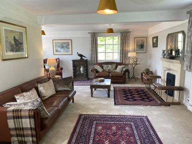 A living room with leather sofas and armchairs rugs a coffee table and a fireplace at Ribby Farmhouse in Lerryn