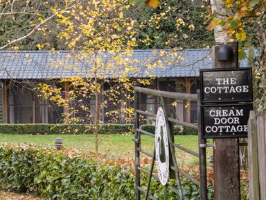 A gated entrance with signs for The Cottage and Cream Door Cottage outside a building surrounded by trees and hedges at Cream Door Cottage Kidderminster