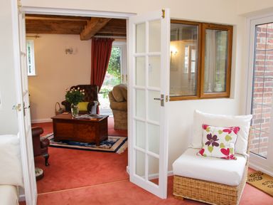 An open white door leading to a living room with a wooden coffee table and armchairs at Cream Door Cottage in Kidderminster