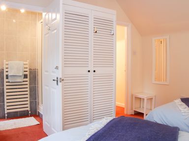 A bedroom with two beds a white wardrobe a bathroom heater with towels and a small white table at Cream Door Cottage in Kidderminster