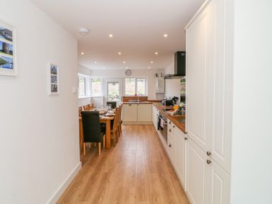 A kitchen and dining area with wooden floors tables and chairs at Llwyd Coed Canol in Llanllyfni near Penygroes